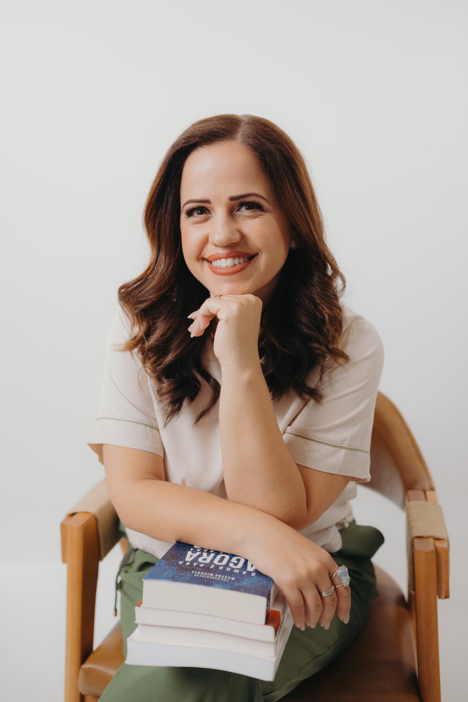 Sarah Carvalho sentada com seus livros